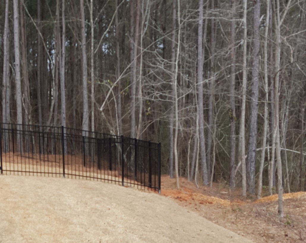 Aluminum ornamental fence panels racked to follow a sloping hillside without gaps at the bottom