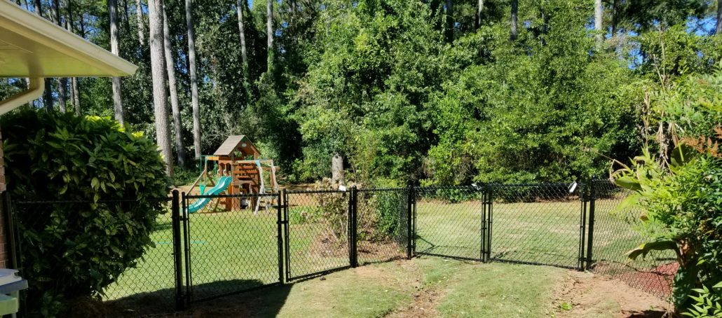 Heavy-duty black chain link double gate installed at a residential driveway entrance