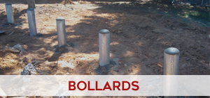 Protective steel bollards installed along a storefront sidewalk for pedestrian safety