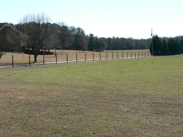 Three-rail farm fence with cross bracing along a pasture in central Georgia