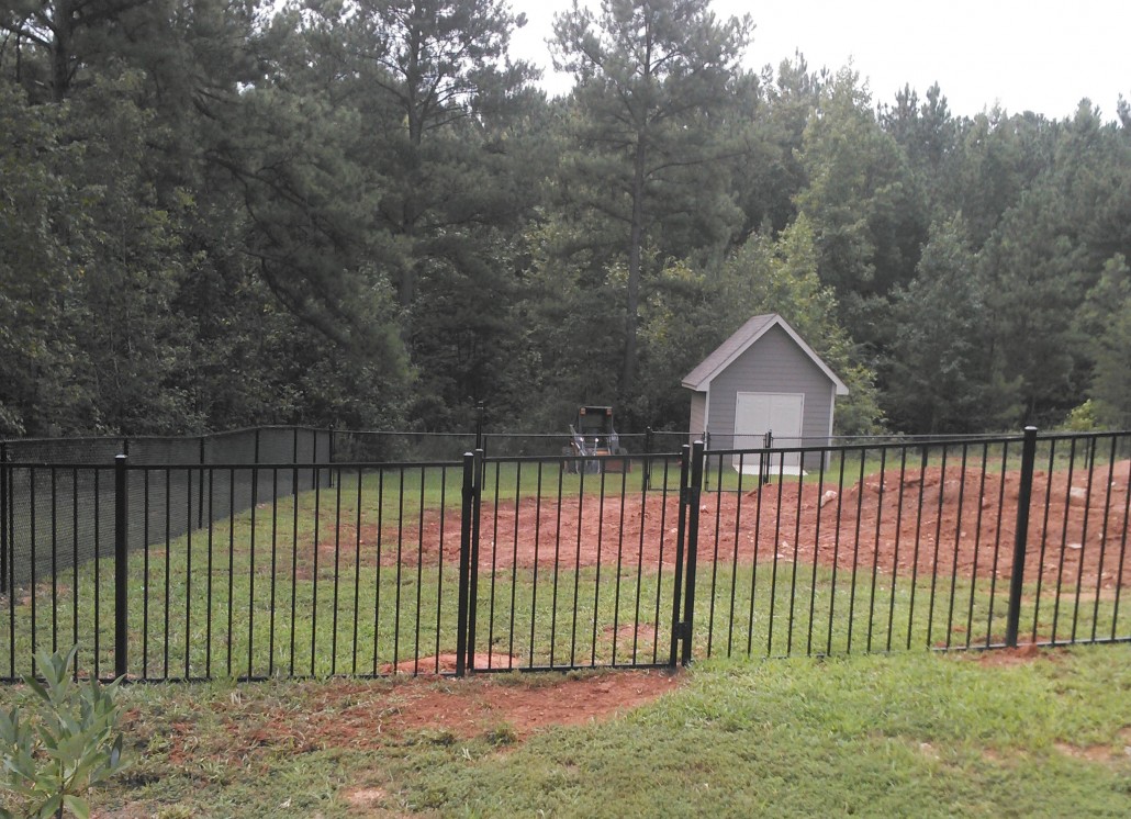 Two-rail ornamental iron fence with spear-top finials bordering a manicured front lawn
