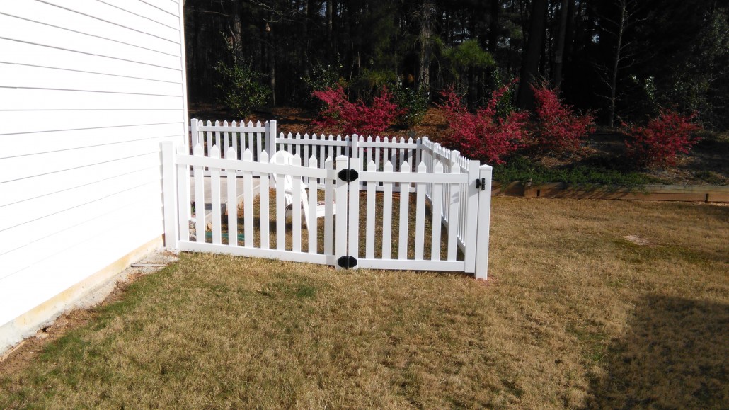 Classic white vinyl picket fence with traditional pointed tops bordering a residential lawn